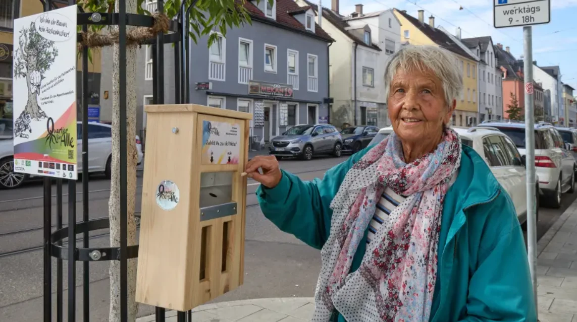 Ältere Frau wirft eine Zigarettenkippe in den hölzernen Aschenbecher an der Wertachstraße